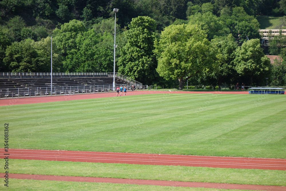 Fototapeta premium Sportstadium mit Personen die Runden laufen an sonnigem Tag