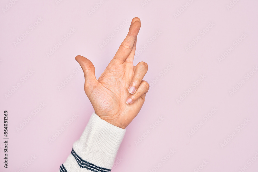 Hand of caucasian young man showing fingers over isolated pink background gesturing fingers crossed, superstition and lucky gesture, lucky and hope expression Hand of caucasian young man showing fingers over isolated pink background gesturing fingers crossed, superstition and lucky gesture, lucky and hope expression