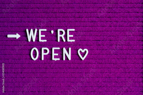 # Reopening plan text on purple letter board near the notebook. Business concept. Service, restaurant, shop and cafe re-opening. Reopening of the place after the quarantine due to covid-19. We're open