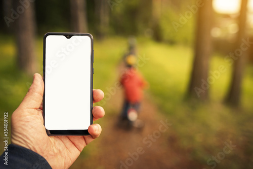 Fototapeta Naklejka Na Ścianę i Meble -  mockup phone image on the blur background of walking children in the forest