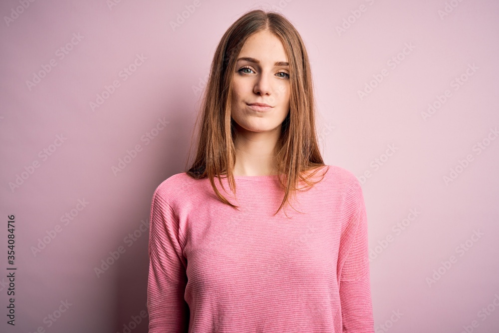 Young beautiful redhead woman wearing casual sweater over isolated pink background Relaxed with serious expression on face. Simple and natural looking at the camera. Young beautiful redhead woman wearing casual sweater over isolated pink background Relaxed with serious expression on face. Simple and natural looking at the camera.