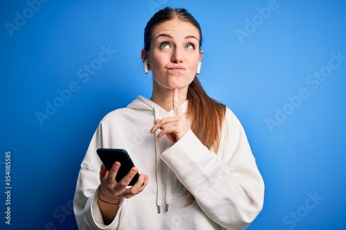 Quadro em tela Young redhead sportswoman doing sport listening to music using earphones and sma