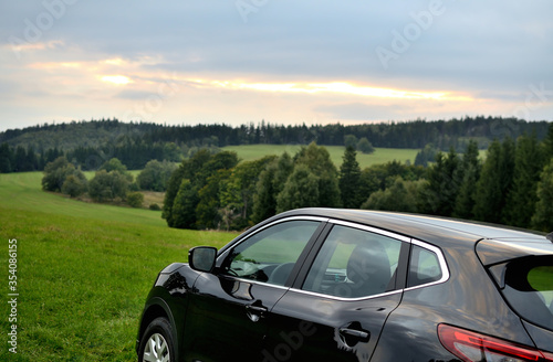 Modern black SUV crossover car vehicle in nature at sunrise. © cobracz