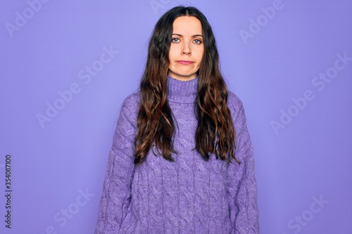 Young beautiful woman wearing casual turtleneck sweater standing over purple background depressed and worry for distress, crying angry and afraid. Sad expression. © Krakenimages.com