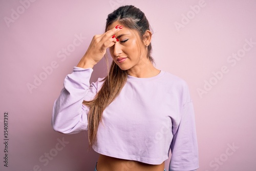Young beautiful sport woman wearing sweatshirt over pink isolated background tired rubbing nose and eyes feeling fatigue and headache. Stress and frustration concept.