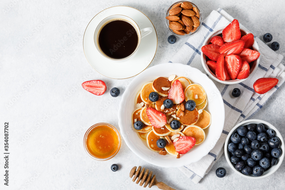 Pancake cereal with honey and berries on white table background Pancake cereal with honey and berries on white table background