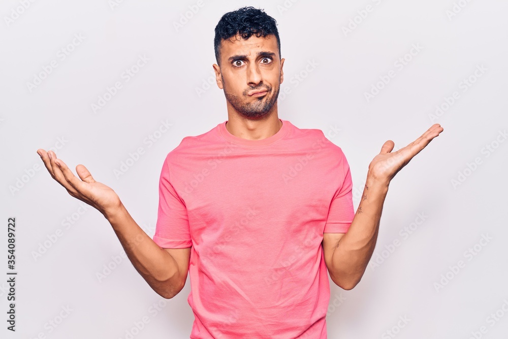 Young hispanic man wearing casual clothes clueless and confused with open arms, no idea and doubtful face. Young hispanic man wearing casual clothes clueless and confused with open arms, no idea and doubtful face.