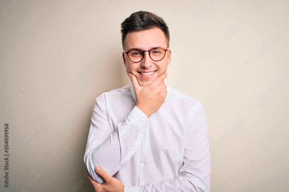 Young handsome business mas wearing glasses and elegant shirt over isolated background looking confident at the camera smiling with crossed arms and hand raised on chin. Thinking positive. Young handsome business mas wearing glasses and elegant shirt over isolated background looking confident at the camera smiling with crossed arms and hand raised on chin. Thinking positive.