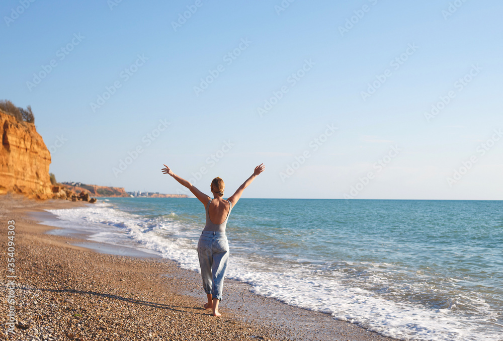 happy woman walks barefoot on the sand by the sea
