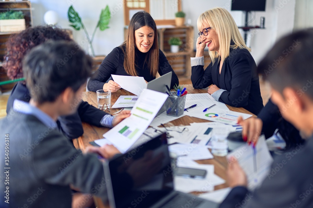 Group of business workers smiling happy and confident. Working together with smile on face using laptop and speaking at the office Group of business workers smiling happy and confident. Working together with smile on face using laptop and speaking at the office