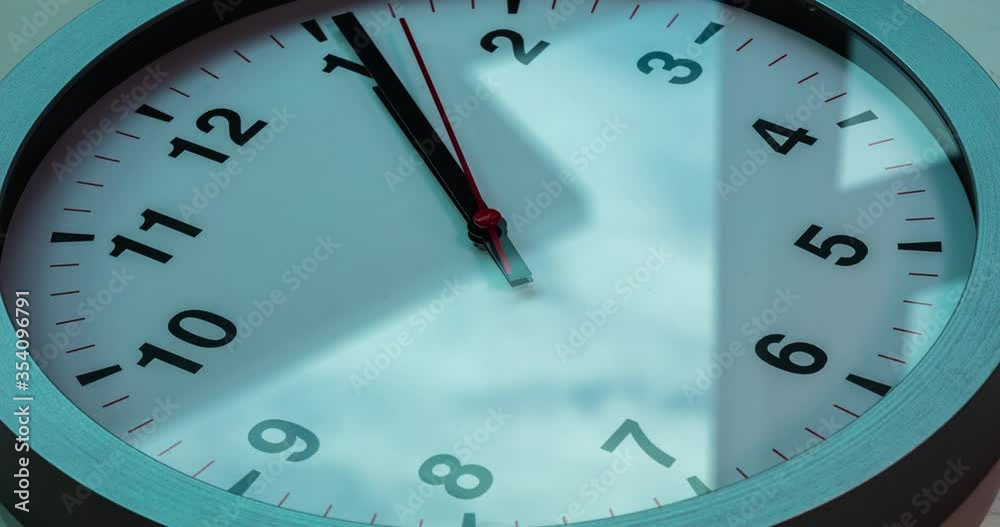 Wall clock show the running time. Time lapse on a modern wall clock. Close up to a wall clock, with running time pointer. Sun and sky reflecting in the watch during the time passing by Wall clock show the running time. Time lapse on a modern wall clock. Close up to a wall clock, with running time pointer. Sun and sky reflecting in the watch during the time passing by