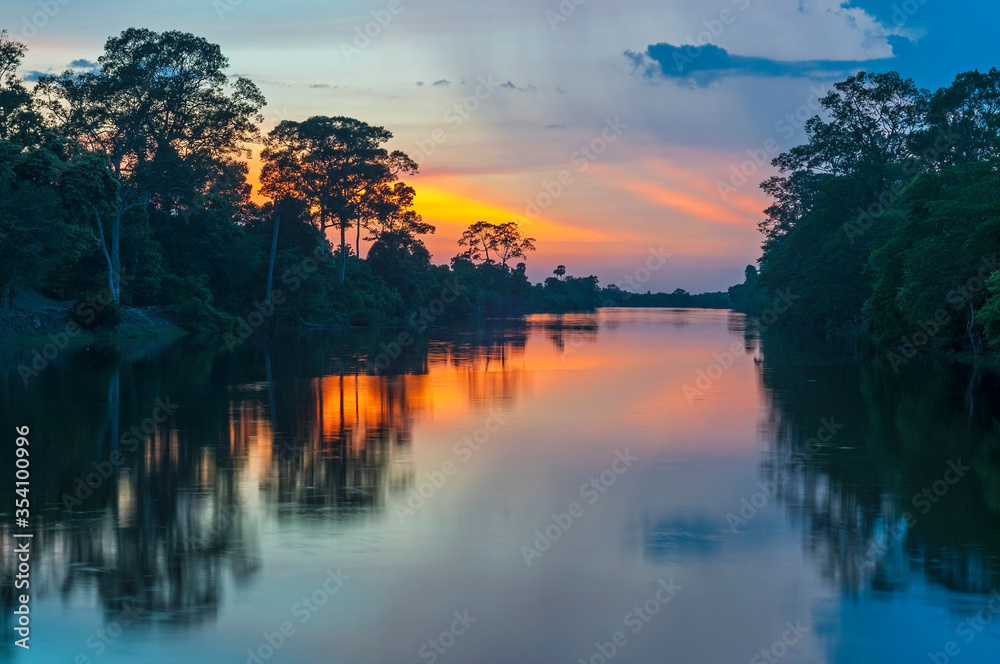 Sunset along the banks of the Amazon river. The tributaries of the Amazon traverse the countries of Guyana, Ecuador, Peru, Brazil, Colombia, Venezuela and Bolivia, Suriname and French Guyana.