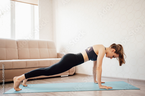 girl is engaged in sports at home online workouts on laptop. pushups and plank