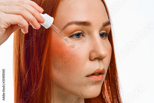 close beauty portrait of a red-haired girl who cleanses the skin with an acidic organic peeling. Isolated on a white background.