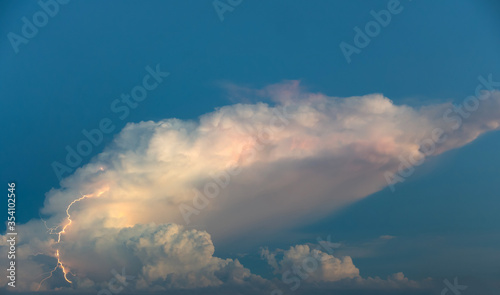 Nature blue sky background - lightnings in sunset sky with dark clouds and rain