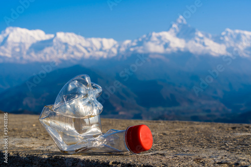 Сrumpled empty plastic bottle on the background of a Annapurna mountain range, Himalaya. Environmental pollution in the tourist regions of the Himalaya mountains.