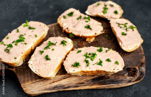  Chicken pate on toast with fresh parsley on a cutting board on a stone background