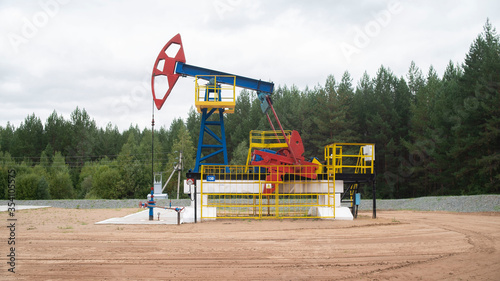 Industrial oil pump jack working and pumping crude oil for fossil fuel energy with drilling rig in oil field. Balancing drive rod pumps oil rocker. Equipment for wellhead connection oil well.