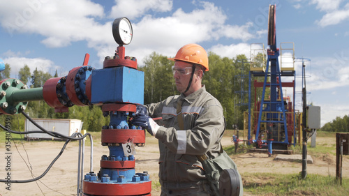 Man oil engineer overseeing Cross type X-mass tree destined for wellhead sealing, their operating regime regulation, installation of electric-centrifugal pump, adjunction of devices for well testing. photo