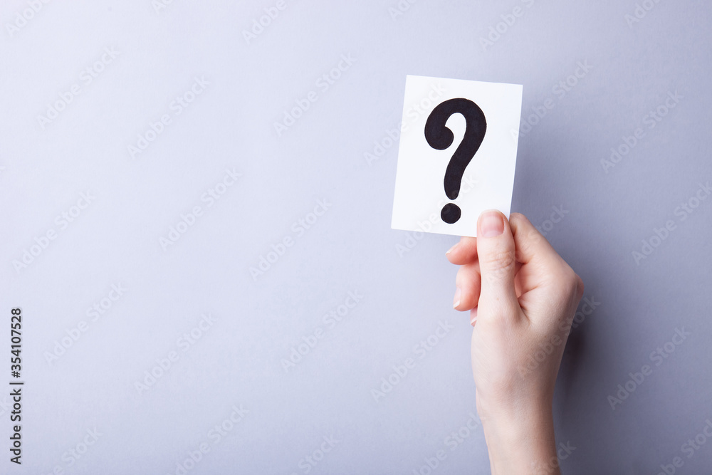 Woman holding card with question mark on color background. Paper note with question mark or sign against grey background, space for text.  Ask or business concept