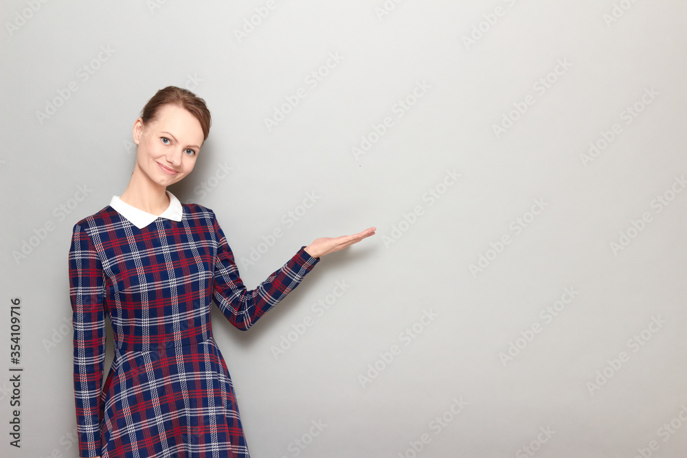 Portrait of pretty cheerful girl pointing with one hand at copy space