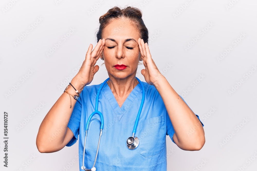 Middle age brunette nurse woman wearing uniform and stethoscope over white background with hand on head, headache because stress. Suffering migraine. Middle age brunette nurse woman wearing uniform and stethoscope over white background with hand on head, headache because stress. Suffering migraine.