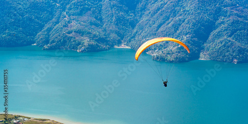 Paragliding in Nepal. Paraglider on the background of Phewa Lake, Pokhara city and surrounding villages. Stock photo.