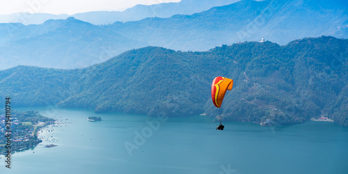 Paragliding in Nepal. Paraglider on the background of Phewa Lake, Pokhara city and surrounding villages. Stock photo.