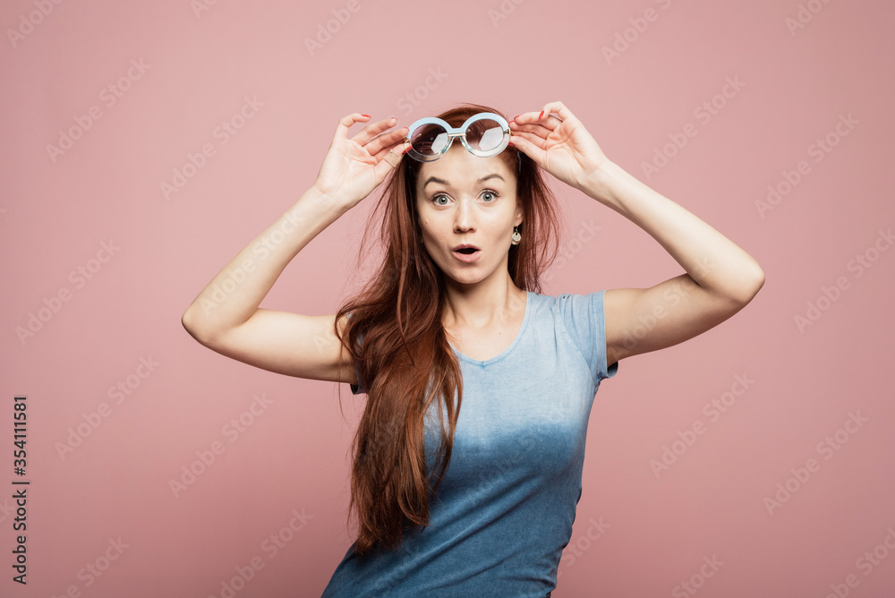 Stunning female model posing with joy face expression on pink background. Portrait of surprised young woman in sunglasses jumping in front of pink wall Stunning female model posing with joy face expression on pink background. Portrait of surprised young woman in sunglasses jumping in front of pink wall