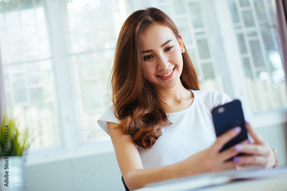 Obraz premium happy young cheerful woman at home office working on smartphone and laptop