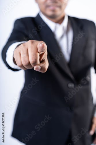 Closed up shot of an asian men pointing at the camera wearing a suit