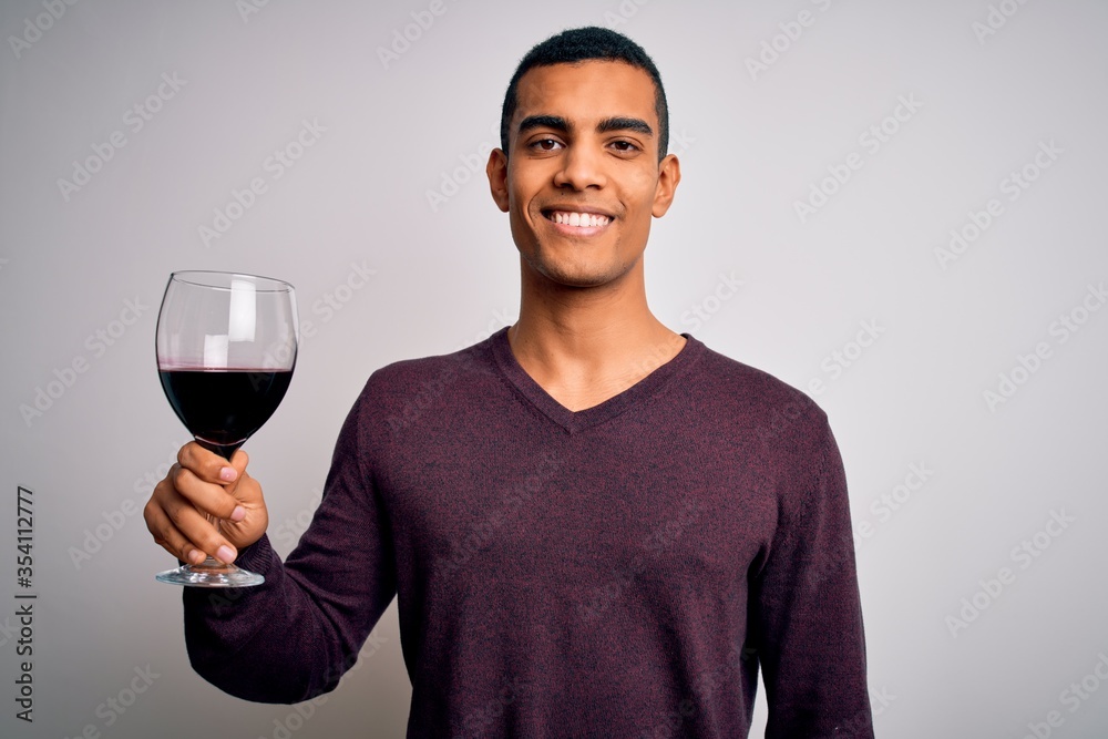 Handsome african american sommelier man tasting glass of red wine over white background with a happy face standing and smiling with a confident smile showing teeth Handsome african american sommelier man tasting glass of red wine over white background with a happy face standing and smiling with a confident smile showing teeth