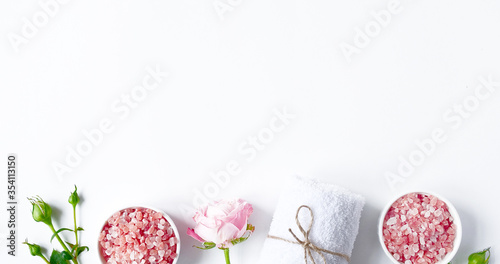 Fototapeta Naklejka Na Ścianę i Meble -  Spa flatlay composition. Sea salt in jar, towel, flower on white background. Top view, copyspace, banner. Daily care concept, relax and rest, bath procedure