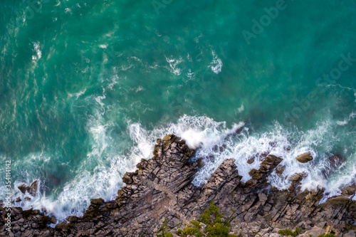 Top down view of Sicilian rocky coast with blue water of Tyrrhenian Sea near Cefalu, Sicily, Italy