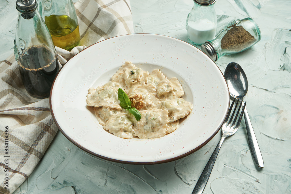 Classic Italian pastry ravioli with the addition of spinach with different fillings (salmon, cheese, vegetables or meat) in a creamy sauce in a beige bowl