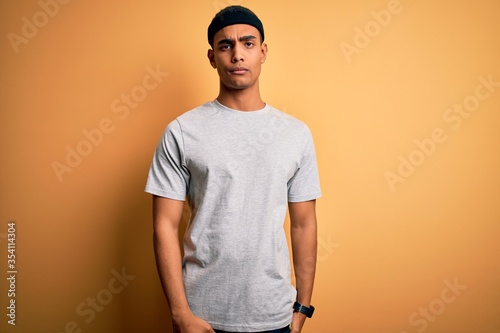 Handsome african american sportsman doing sport wearing sportswear over yellow background looking sleepy and tired, exhausted for fatigue and hangover, lazy eyes in the morning. © Krakenimages.com