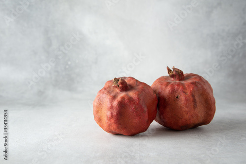 Two dried ugly pomegranates on a gray background with copy space.