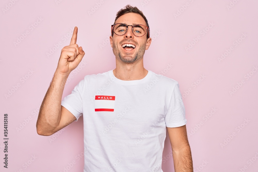 Handsome man with blue eyes wearing sticker with hello my name is ...