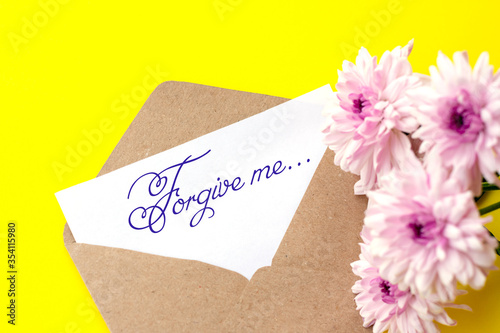 Love envelope and letter with written words forfive me with pink chrysanthemum flowers on bright yellow bacground.