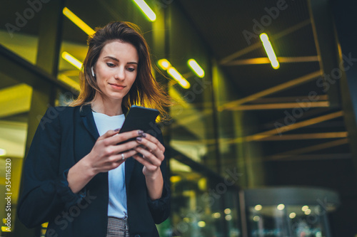 Fotografiet Successful female banker using smartphone outdoors while standing near his offic