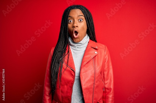 Young african american woman wearing cool fashion leather jacket over red isolated background afraid and shocked with surprise expression  fear and excited face.