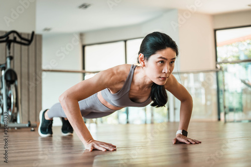 Beautiful young Asian woman doing push ups in the gym