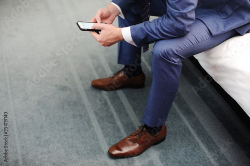 Man in blue suit with typing on phone and shoes