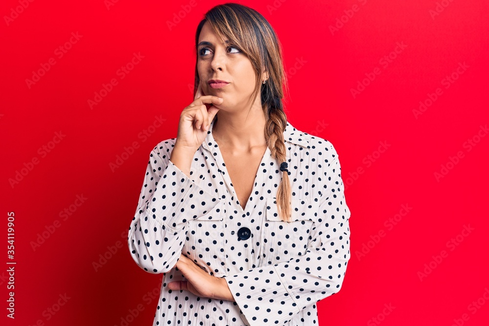 Young beautiful woman wearing casual dress thinking concentrated about doubt with finger on chin and looking up wondering Young beautiful woman wearing casual dress thinking concentrated about doubt with finger on chin and looking up wondering
