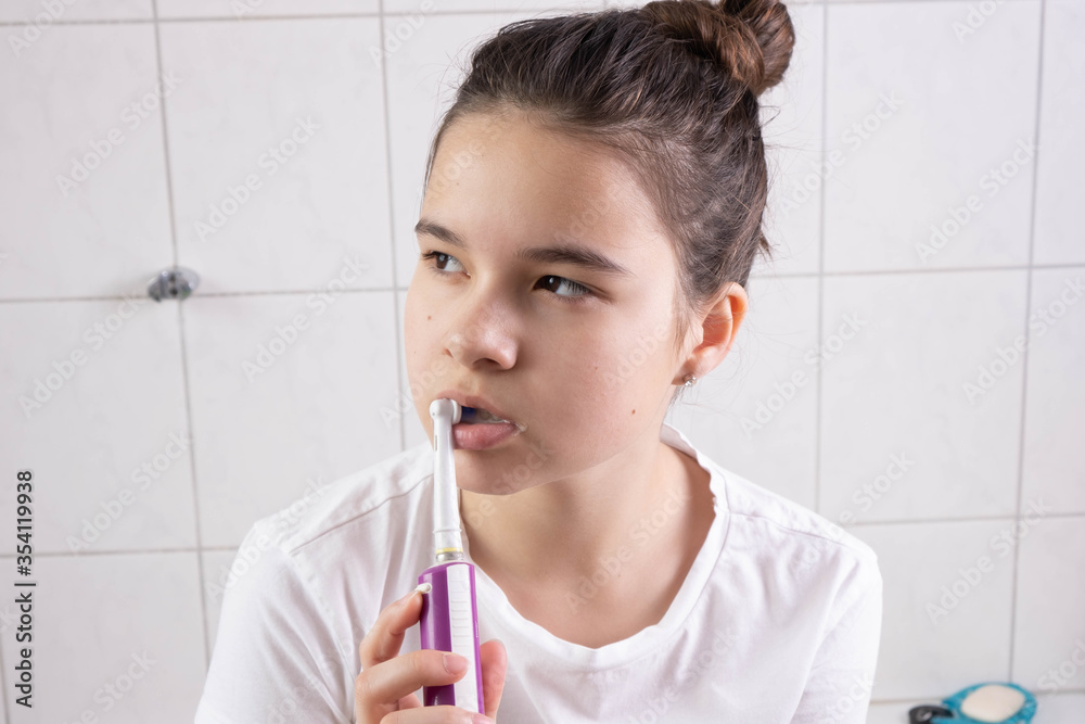 girl brushes her teeth with an electric brush in the bathroom girl brushes her teeth with an electric brush in the bathroom