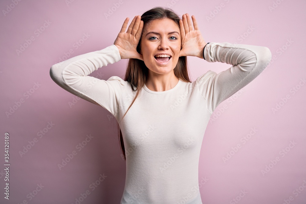 Young beautiful woman with blue eyes wearing casual white t-shirt over pink background Smiling cheerful playing peek a boo with hands showing face. Surprised and exited Young beautiful woman with blue eyes wearing casual white t-shirt over pink background Smiling cheerful playing peek a boo with hands showing face. Surprised and exited