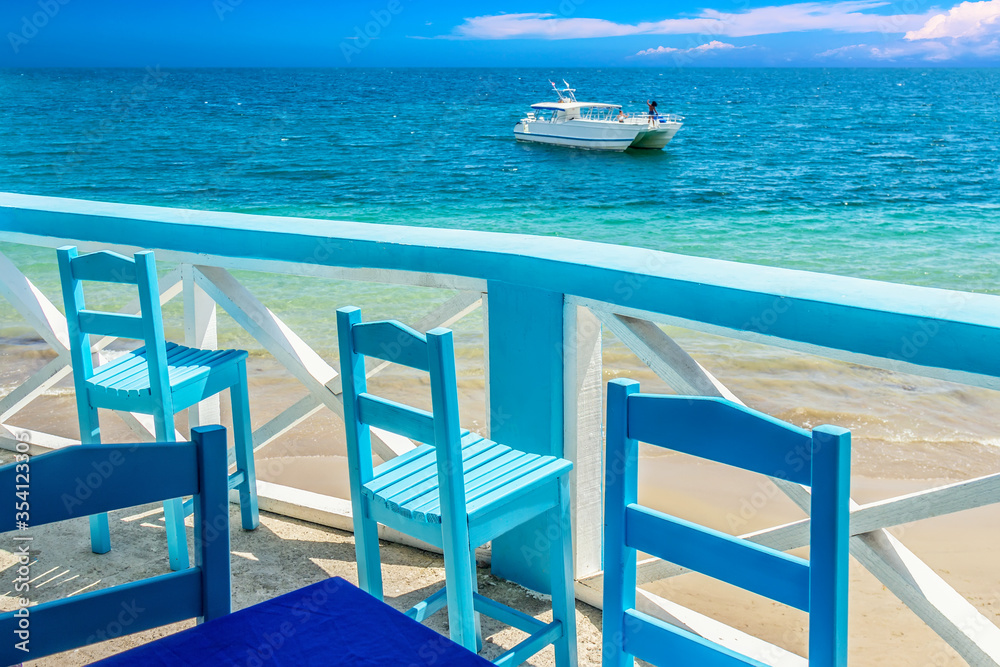 Beautiful panoramic view point with blue chairs and a ship. Vacation background. Idyllic beach landscape in Samana, Dominican Republic Beautiful panoramic view point with blue chairs and a ship. Vacation background. Idyllic beach landscape in Samana, Dominican Republic