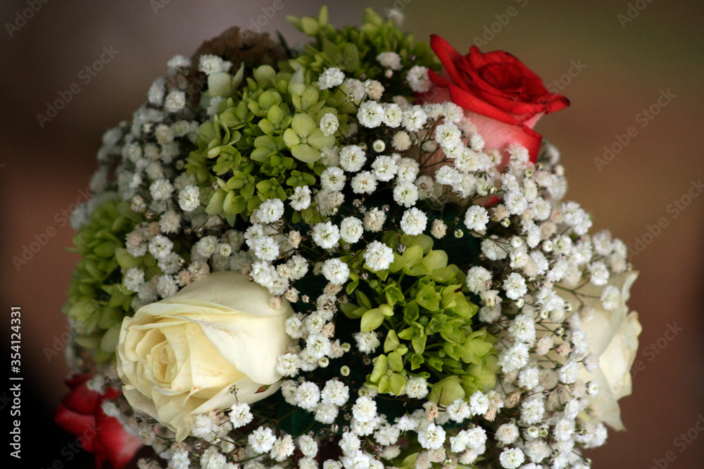 closeup to beautiful bouquet of white and red wedding ceremony roses with small foliage