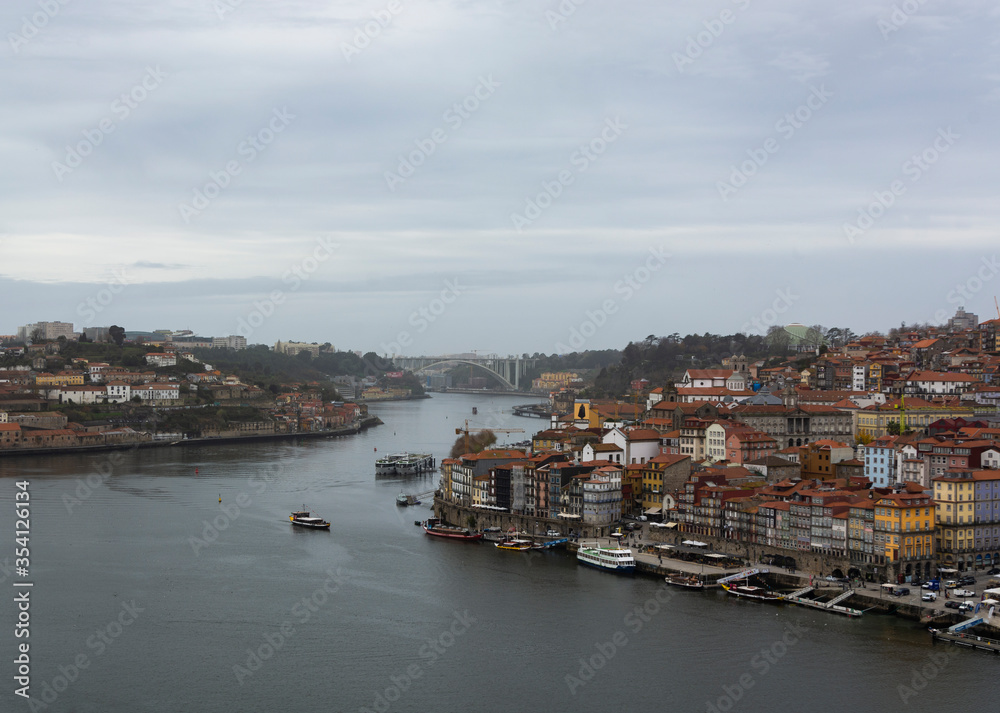 Porto, Portugal. View to the city of Porto (Portugal) and Douro river. Douro river with boats. Ribeira e Vila Nova de Gaia. Cloudy sky.