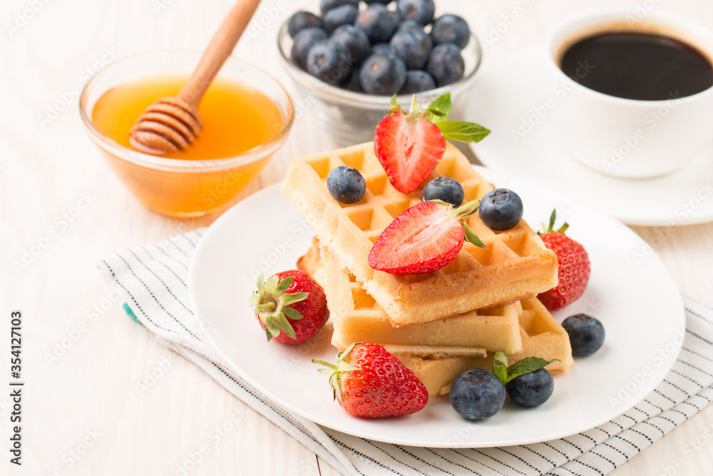 Photo of fresh homemade food made of Belgian waffles with honey, chocolate, strawberry, blueberry. Healthy dessert breakfast concept. Photo of fresh homemade food made of Belgian waffles with honey, chocolate, strawberry, blueberry. Healthy dessert breakfast concept.